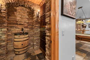 Stone-clad wine cellar featuring a wood rack system and overhead wood ceiling