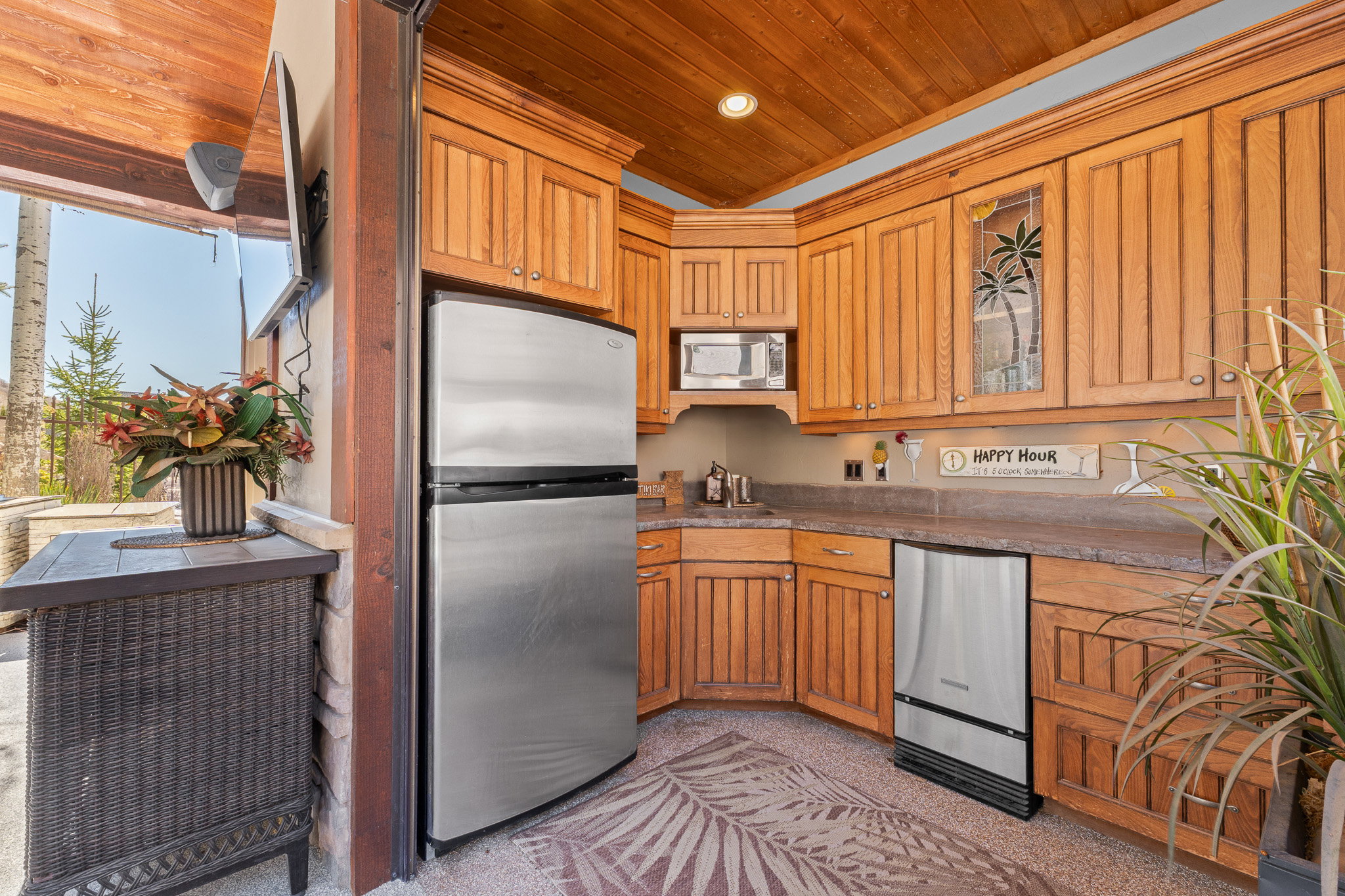 Outdoor kitchen featuring wood-finish cabinetry, stainless steel appliances, and a wood-paneled ceiling