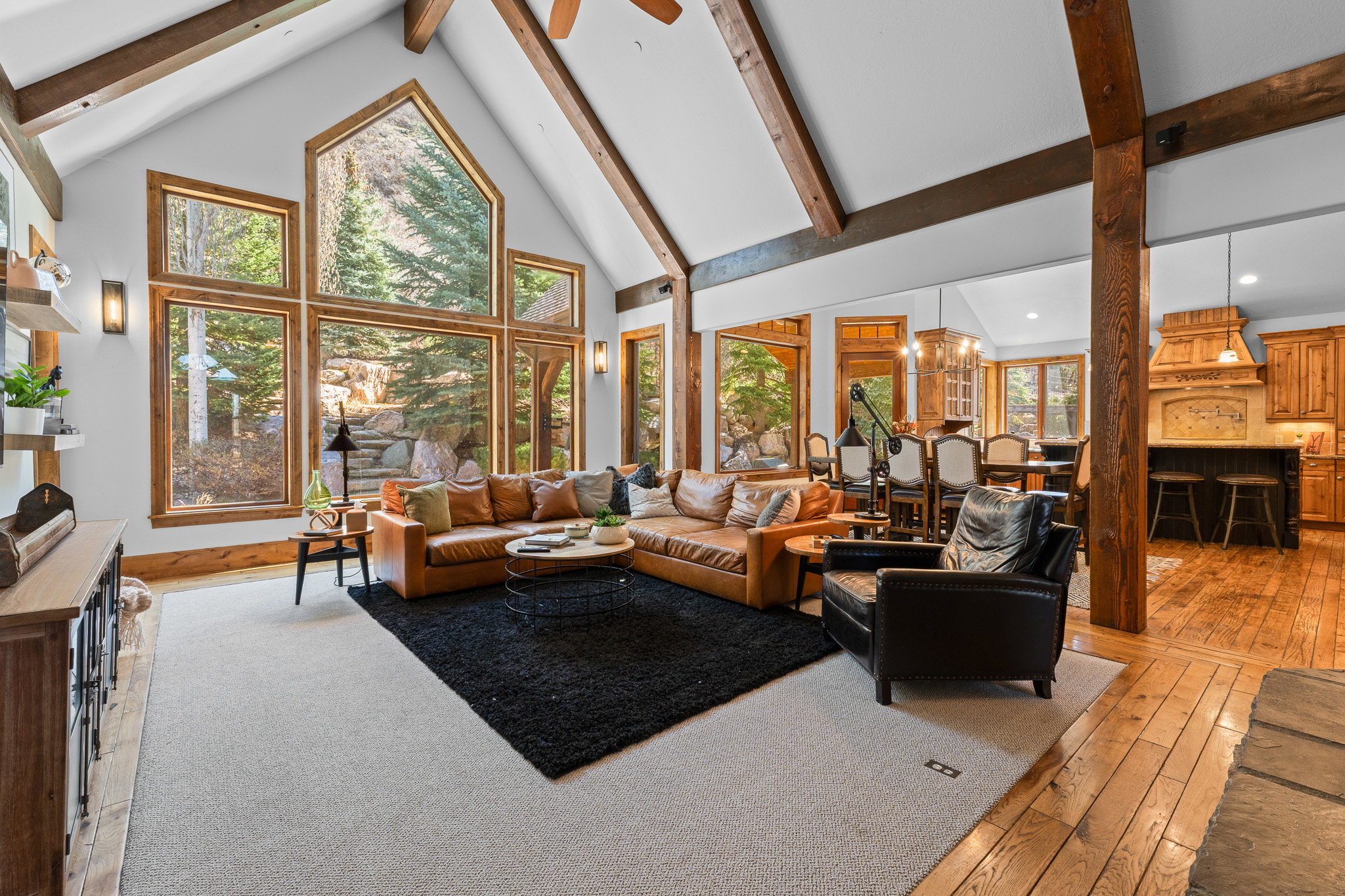 Vaulted living space featuring exposed wood beams and a wall of floor-to-ceiling windows