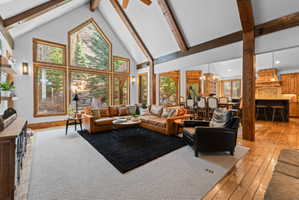 Vaulted living space featuring exposed wood beams and a wall of floor-to-ceiling windows