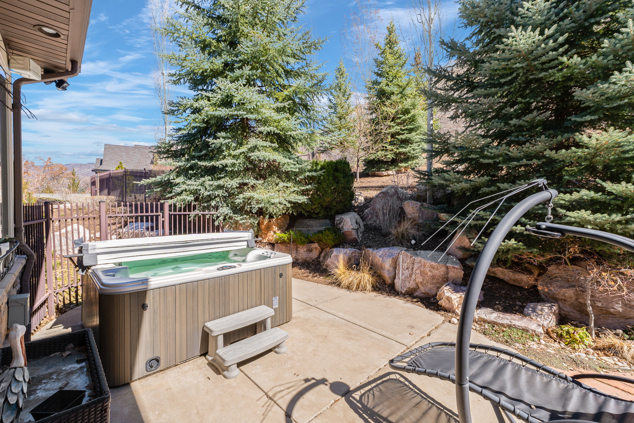 Outdoor patio featuring a built-in hot tub with steps and a privacy fence