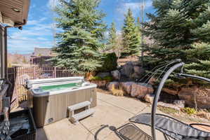 Outdoor patio featuring a built-in hot tub with steps and a privacy fence