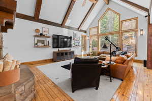 Vaulted ceilings with exposed wood beams define this spacious living area, featuring a stone fireplace