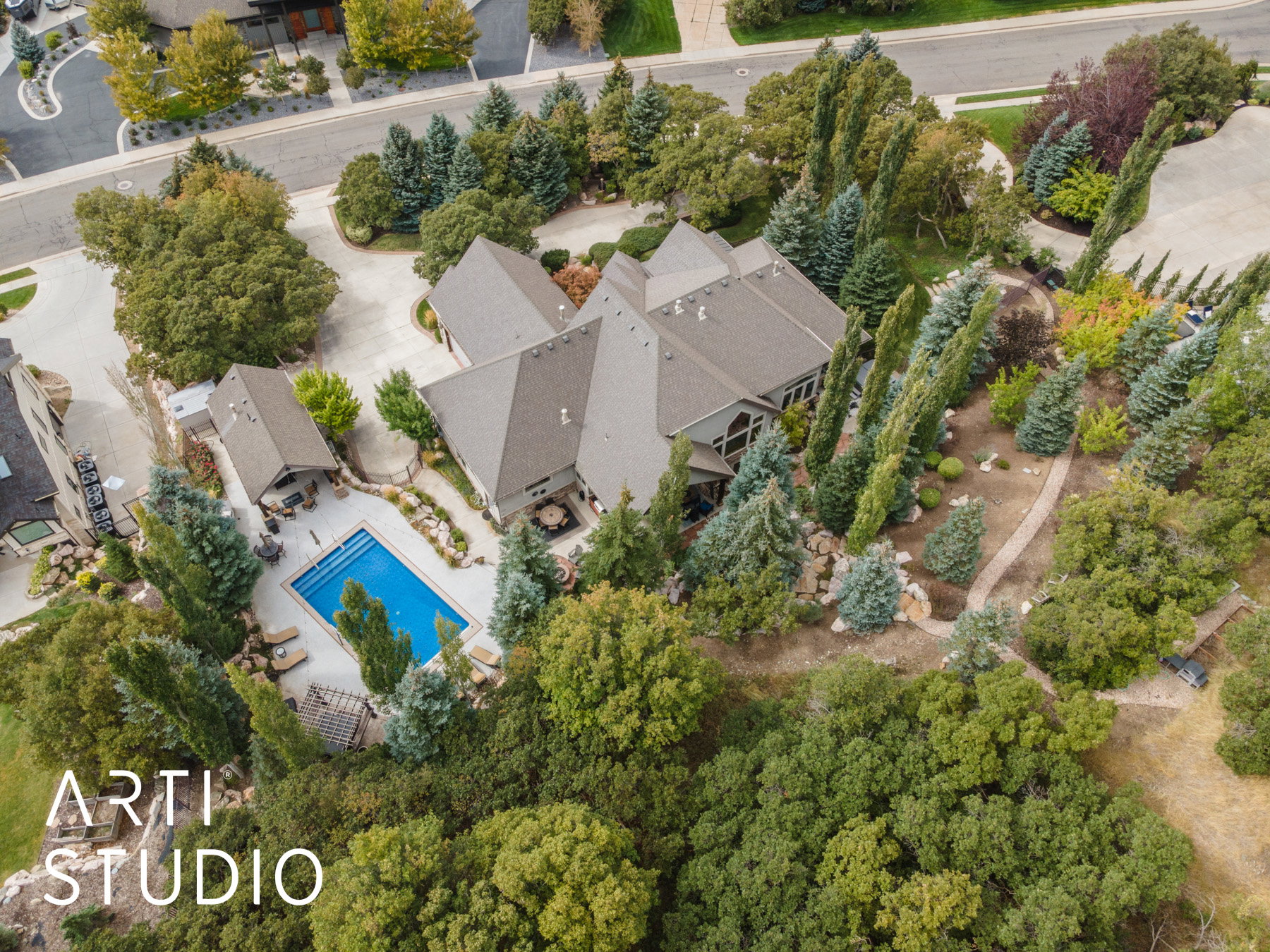 Expansive private grounds featuring a rectangular swimming pool, a separate pool house structure, and extensive mature landscaping with varied tree species