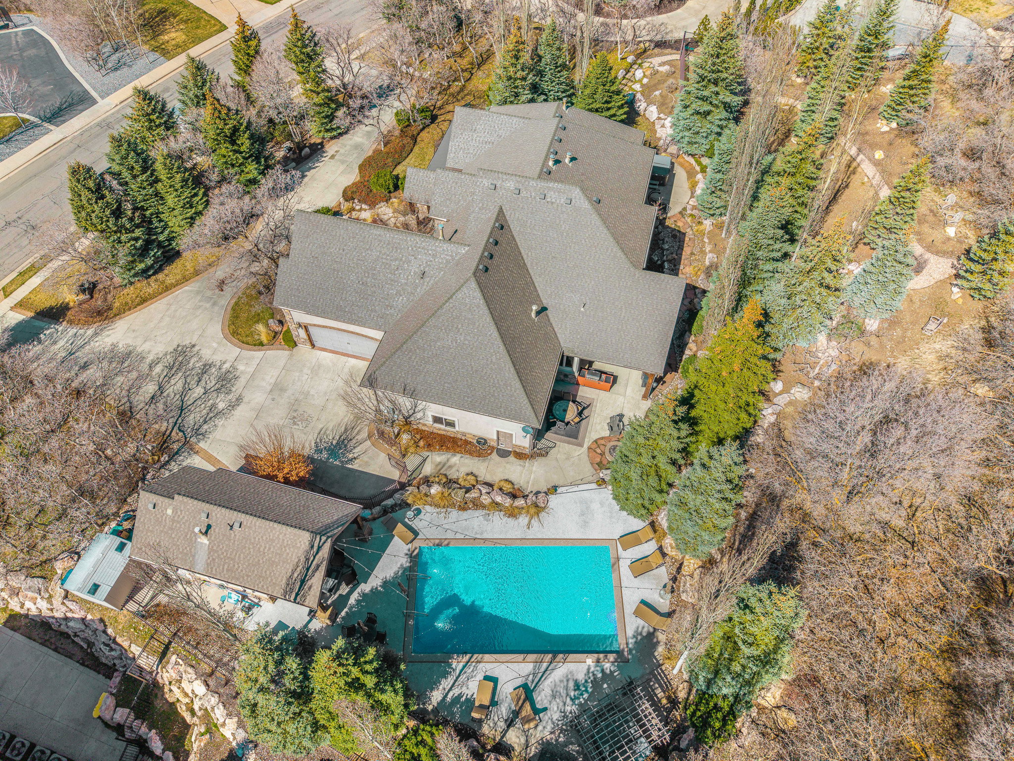 Expansive property featuring a multi-level main residence, a detached auxiliary building, and a rectangular swimming pool