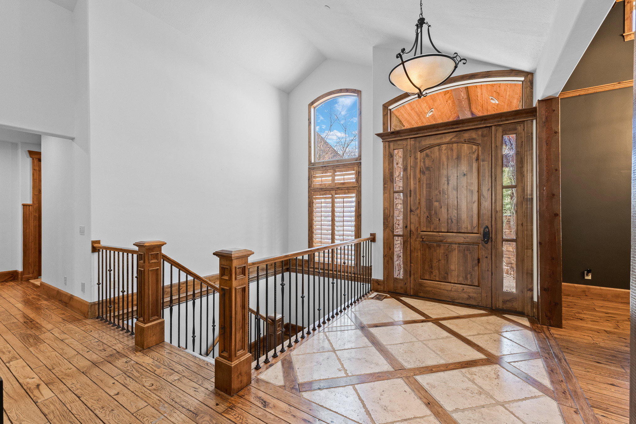 Grand entry featuring a solid wood door with decorative glass sidelights and an arched transom window