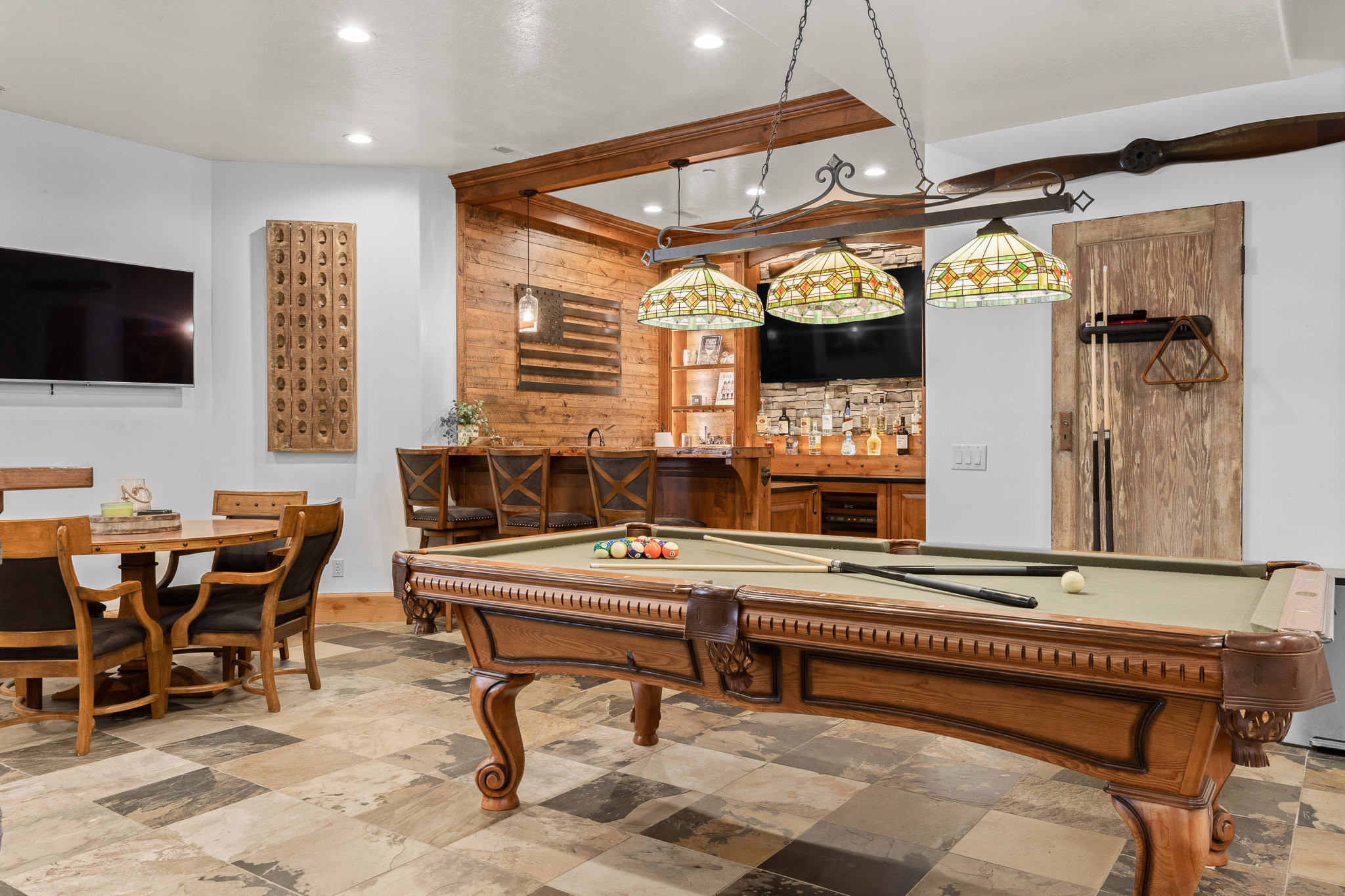 Recreational area featuring a pool table with Tiffany-style lighting, a built-in bar with stone backsplash, and multi-toned tile flooring
