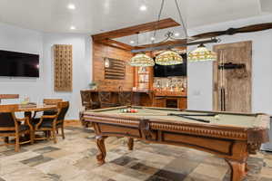 Recreational area featuring a pool table with Tiffany-style lighting, a built-in bar with stone backsplash, and multi-toned tile flooring