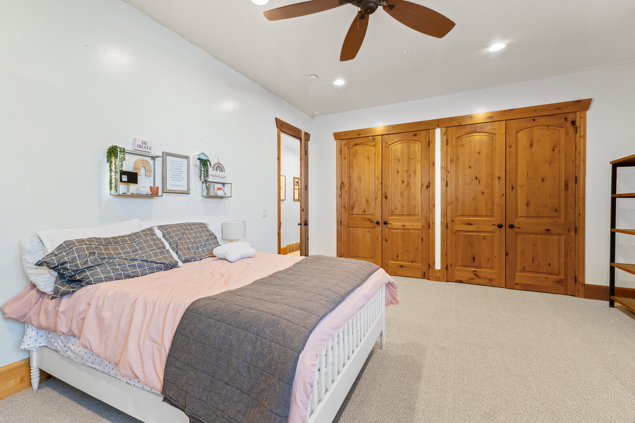 Spacious room featuring light-toned carpet flooring, a wood-finish ceiling fan, and recessed lighting