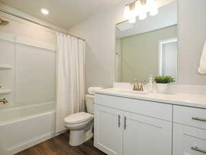 Full bathroom featuring a white vanity with a speckled countertop, a large frameless mirror, and a three-light fixture