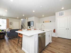 Kitchen island with a built-in stainless steel sink, integrated dishwasher, and white countertop seating