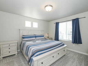 Bedroom featuring carpet flooring, natural light from a window with blinds, and two square transom windows