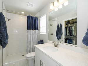 Bathroom featuring a white subway tile shower, white vanity with an integrated sink, polished chrome faucet, and overhead lighting