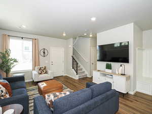 Open-concept living space featuring wood-finish flooring, recessed lighting, a built-in media console, and an integrated bench with beadboard detailing