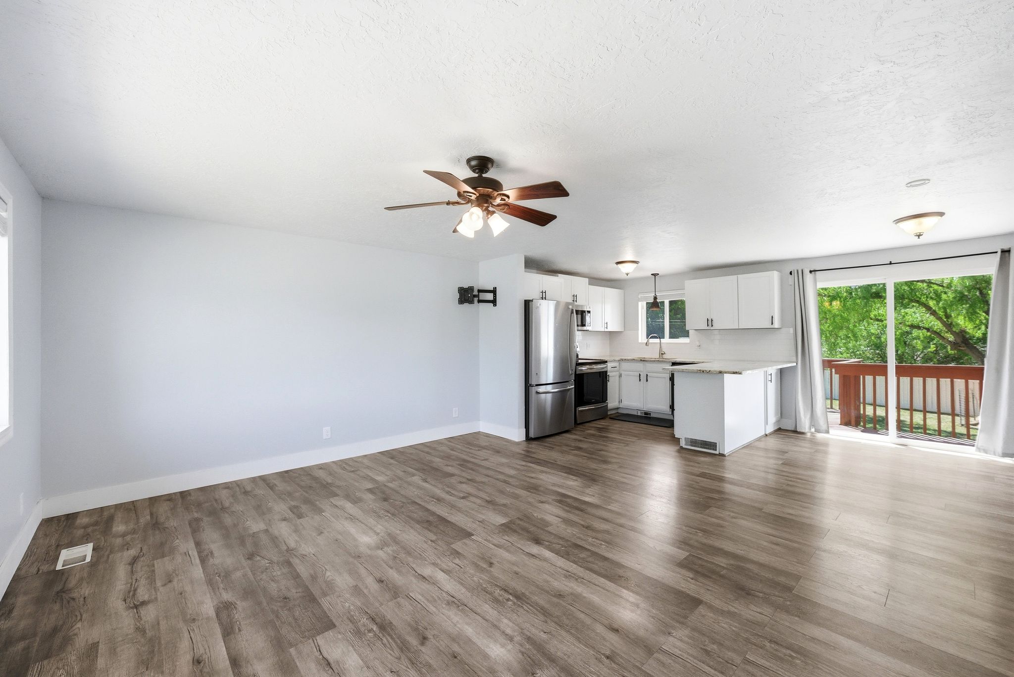Open-concept living area featuring wood-finish flooring, a ceiling fan, and white walls