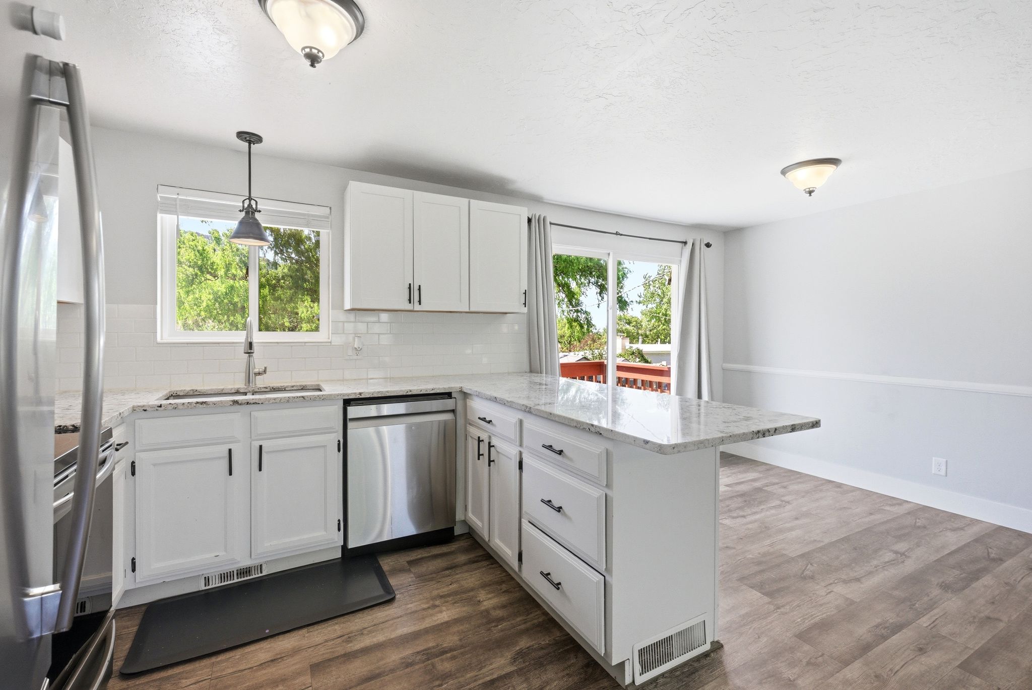 Modern kitchen featuring white cabinetry, stainless steel appliances, a white subway tile backsplash, and a light-toned countertop