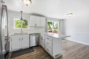 Modern kitchen featuring white cabinetry, stainless steel appliances, a white subway tile backsplash, and a light-toned countertop