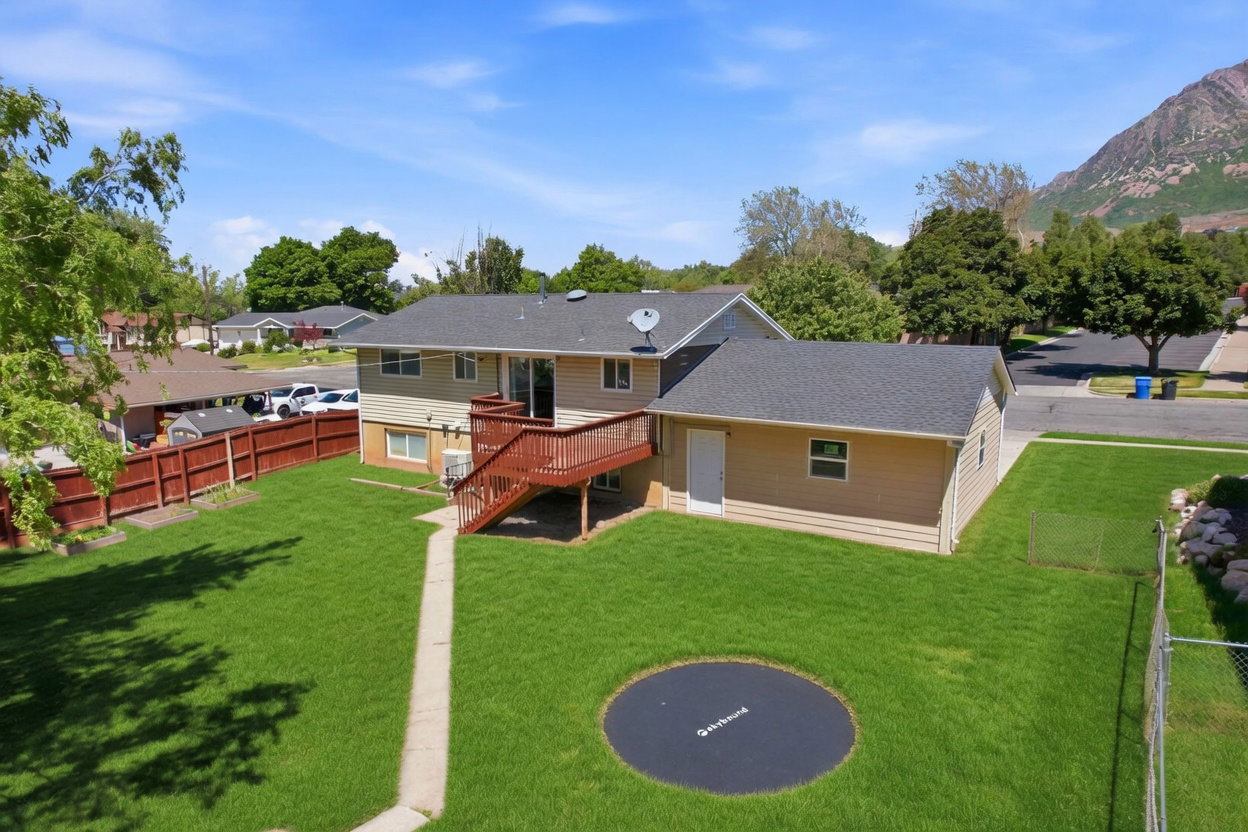 Spacious rear yard featuring an expansive lawn, a multi-level wood deck, and a concrete pathway