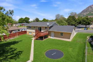 Spacious rear yard featuring an expansive lawn, a multi-level wood deck, and a concrete pathway