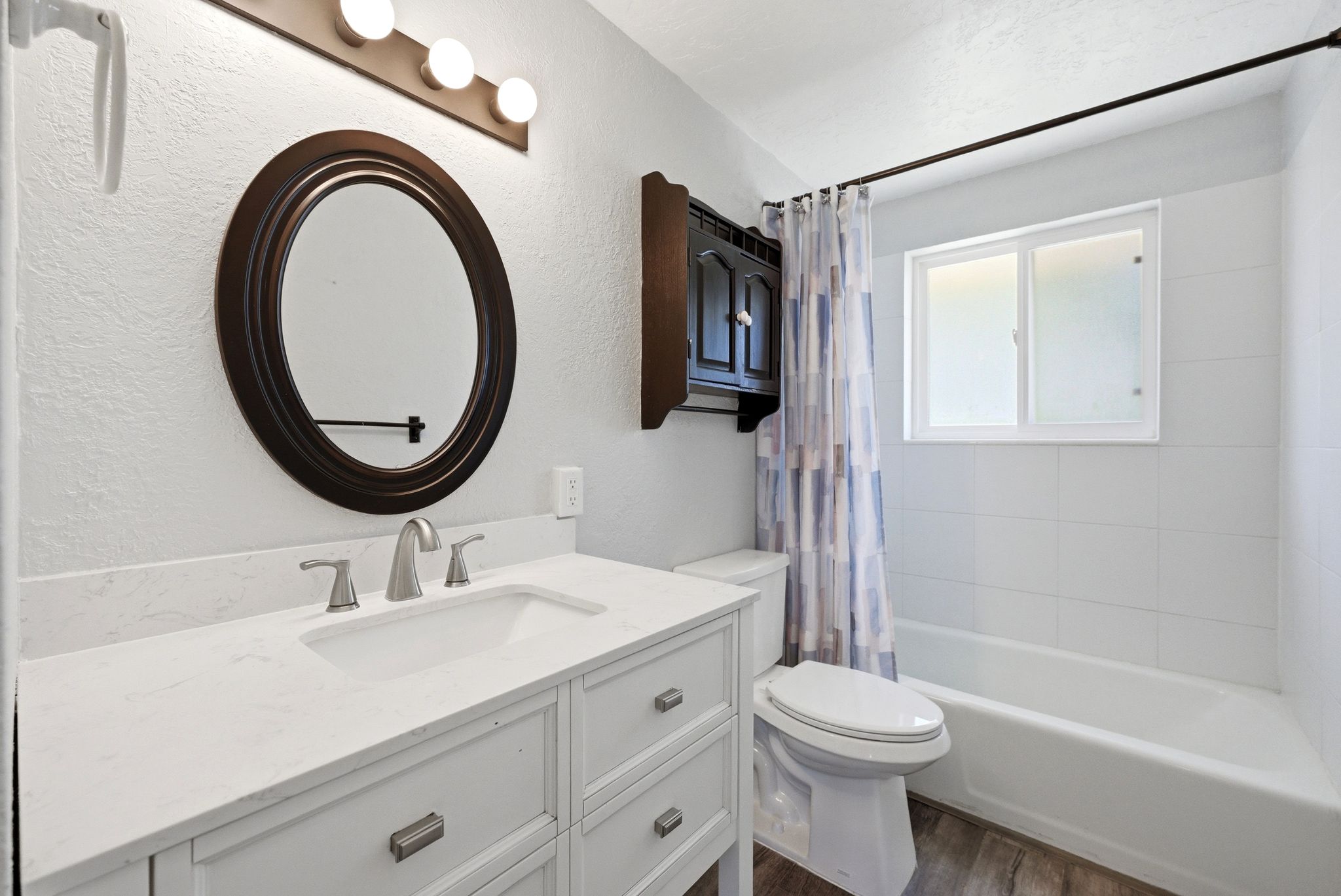 Bathroom featuring a white vanity with an undermount sink, brushed nickel faucet, and a large oval mirror