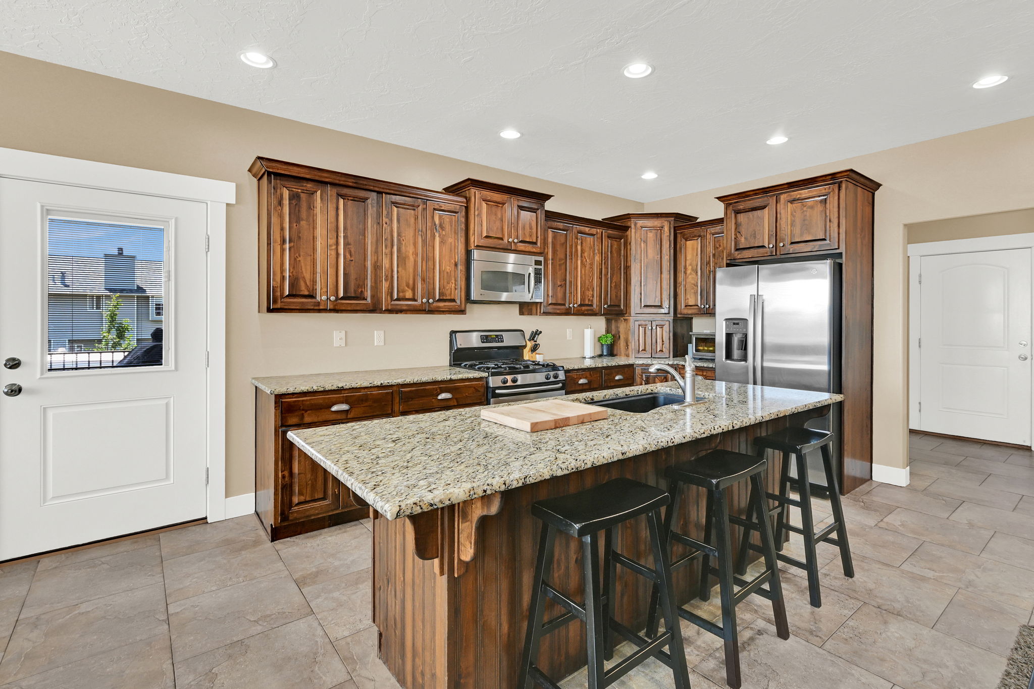Kitchen featuring wood-finish cabinetry, granite countertops, stainless steel appliances, and tile flooring