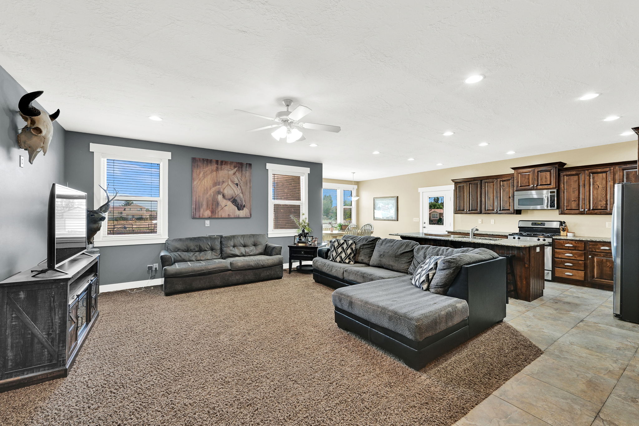 Open-concept living area featuring a ceiling fan, recessed lighting, and carpet flooring