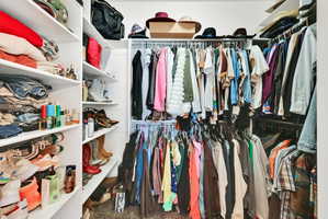 Walk-in closet featuring built-in shelving, multiple hanging rods, and integrated storage solutions