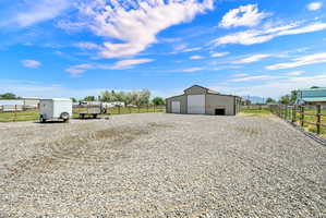 Expansive gravel lot featuring a large outbuilding with multiple garage doors and a separate entry