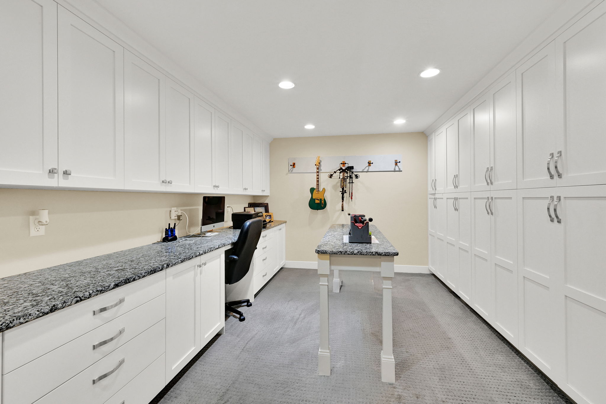 Dedicated functional room featuring extensive white cabinetry, recessed lighting, a stone-finish countertop workspace, and carpeted flooring