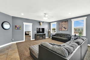 Carpeted living area featuring recessed lighting, a ceiling fan, and multiple windows