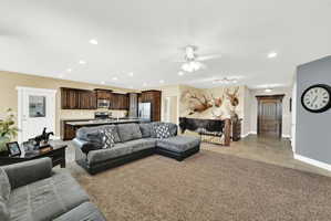 Open-concept main living area featuring wood-finish cabinetry, stainless steel appliances, and a central island with countertop seating