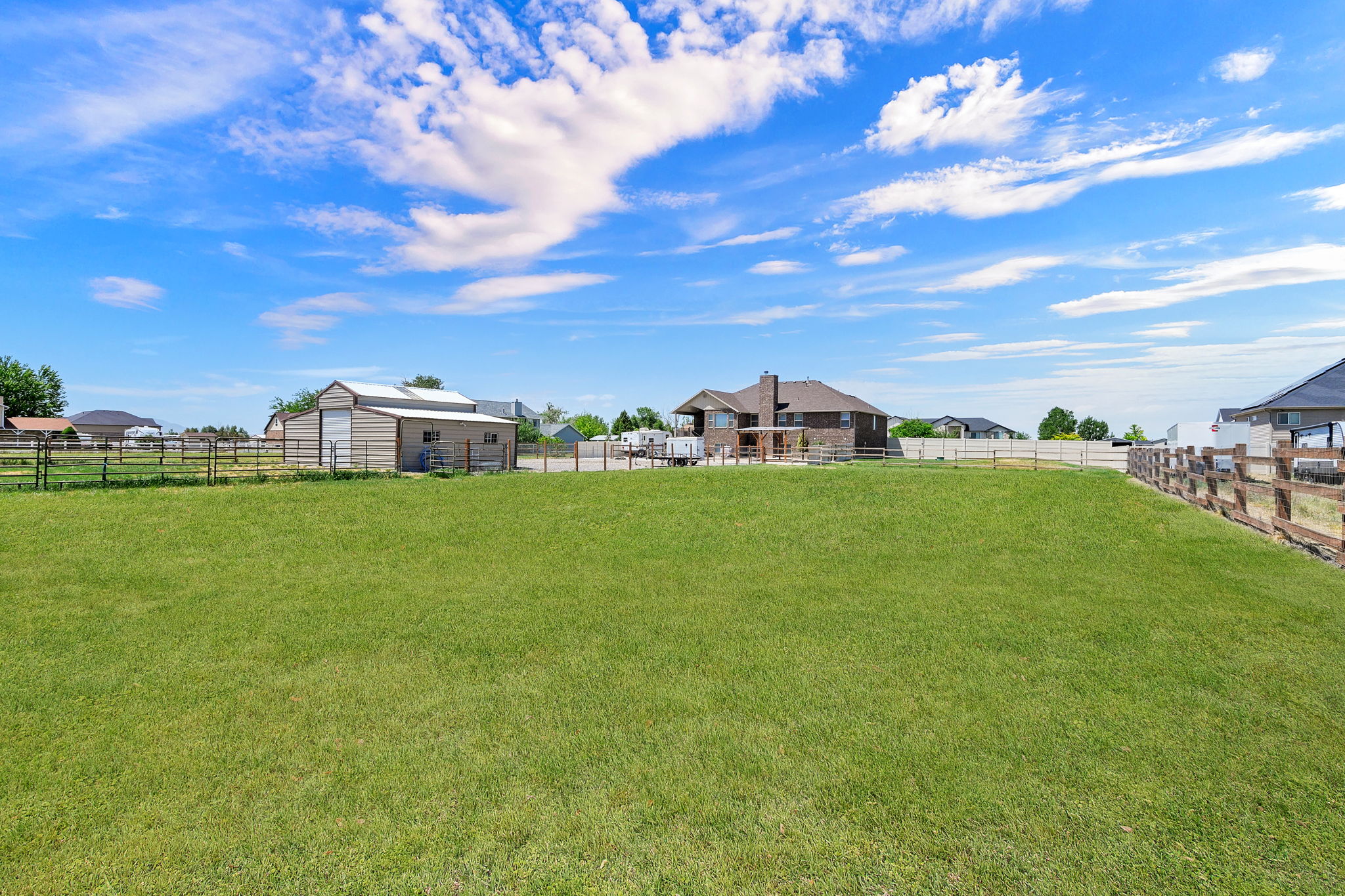 Expansive green lawn area featuring a wood rail fence