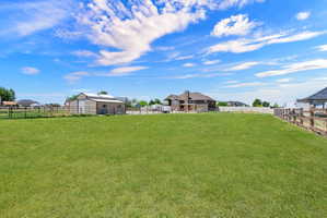 Expansive green lawn area featuring a wood rail fence