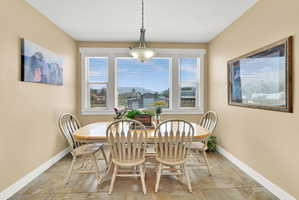 Dining area featuring multiple windows with blinds, a rectangular chandelier, and tile flooring