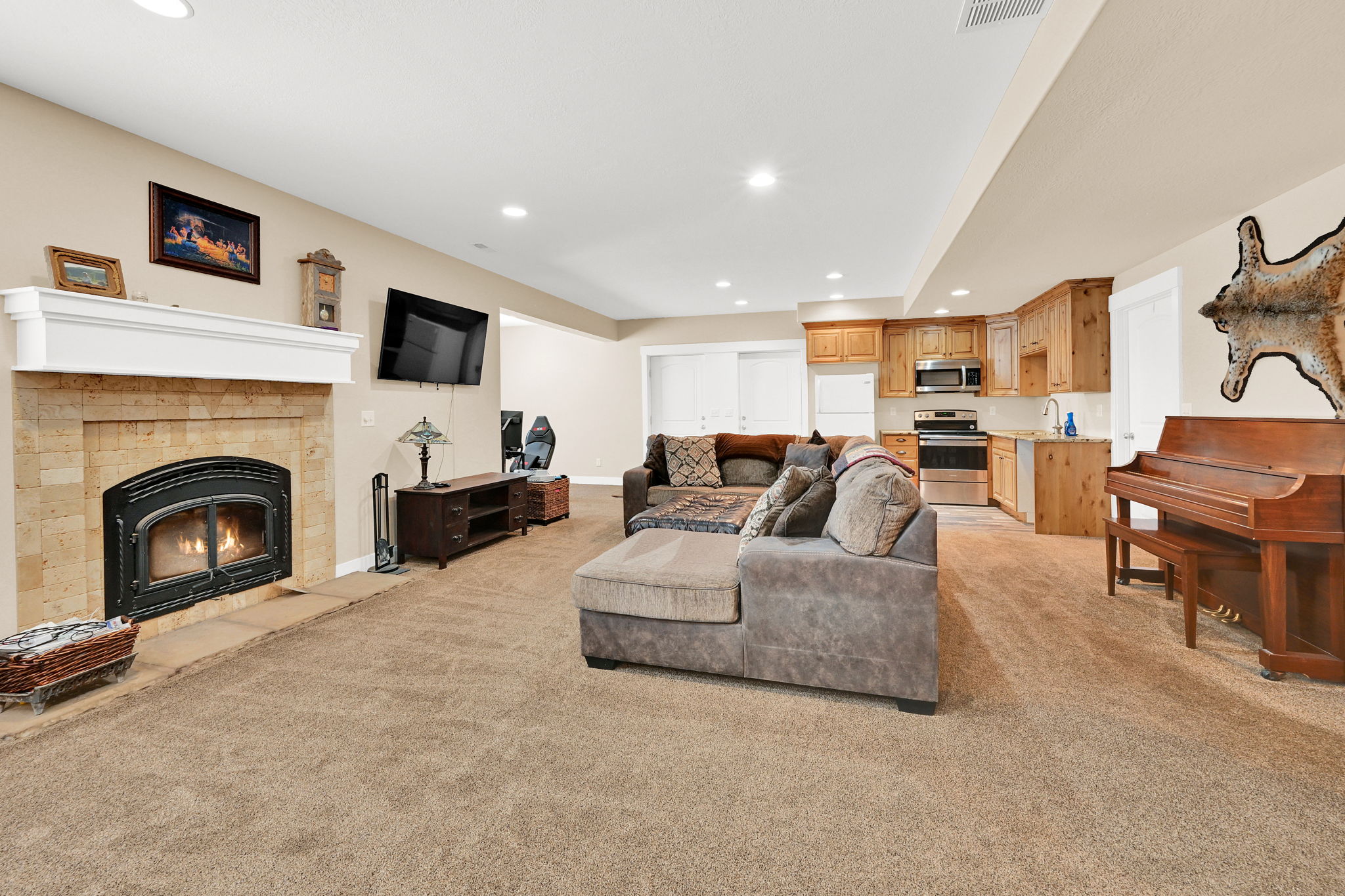 Open-concept living space featuring a gas fireplace with a white mantel and stone surround