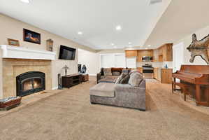 Open-concept living space featuring a gas fireplace with a white mantel and stone surround