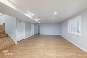 Spacious room featuring wood-finish flooring, recessed lighting, and a window with white louvered shutters