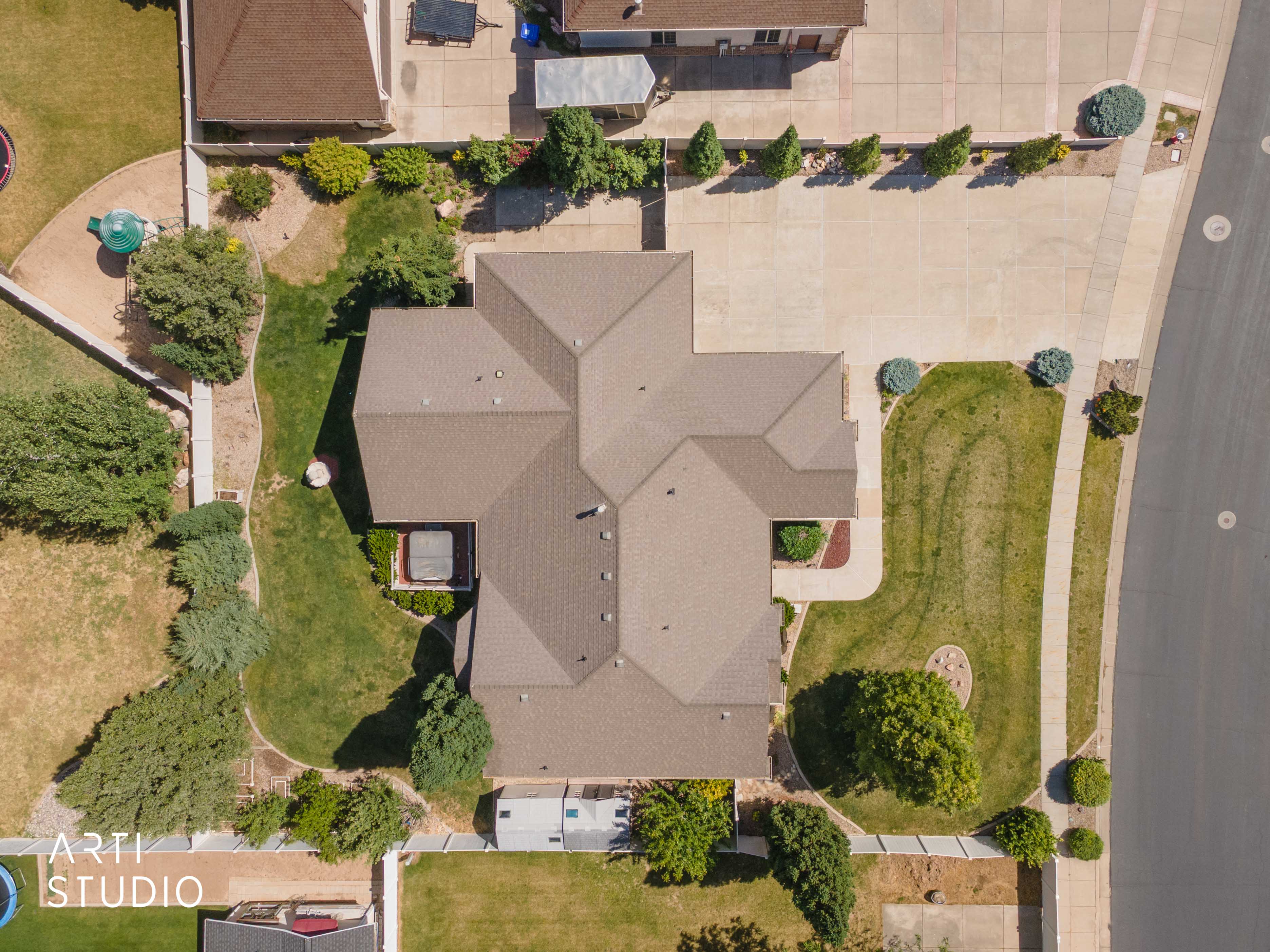 Extensive concrete driveway, mature landscaping, and an architectural shingle roof