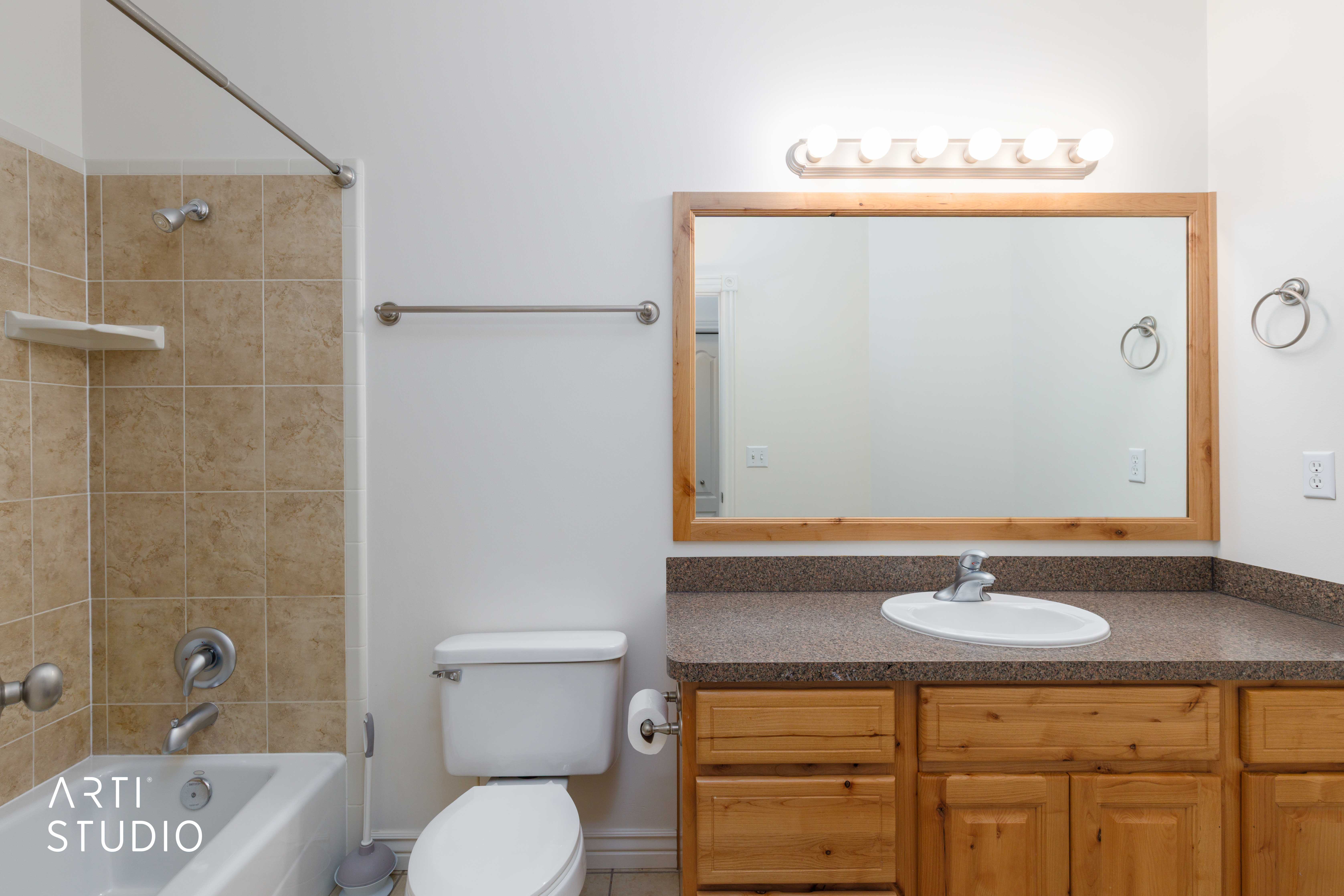 Bathroom featuring a single vanity with wood cabinetry, a built-in sink, and a speckled countertop