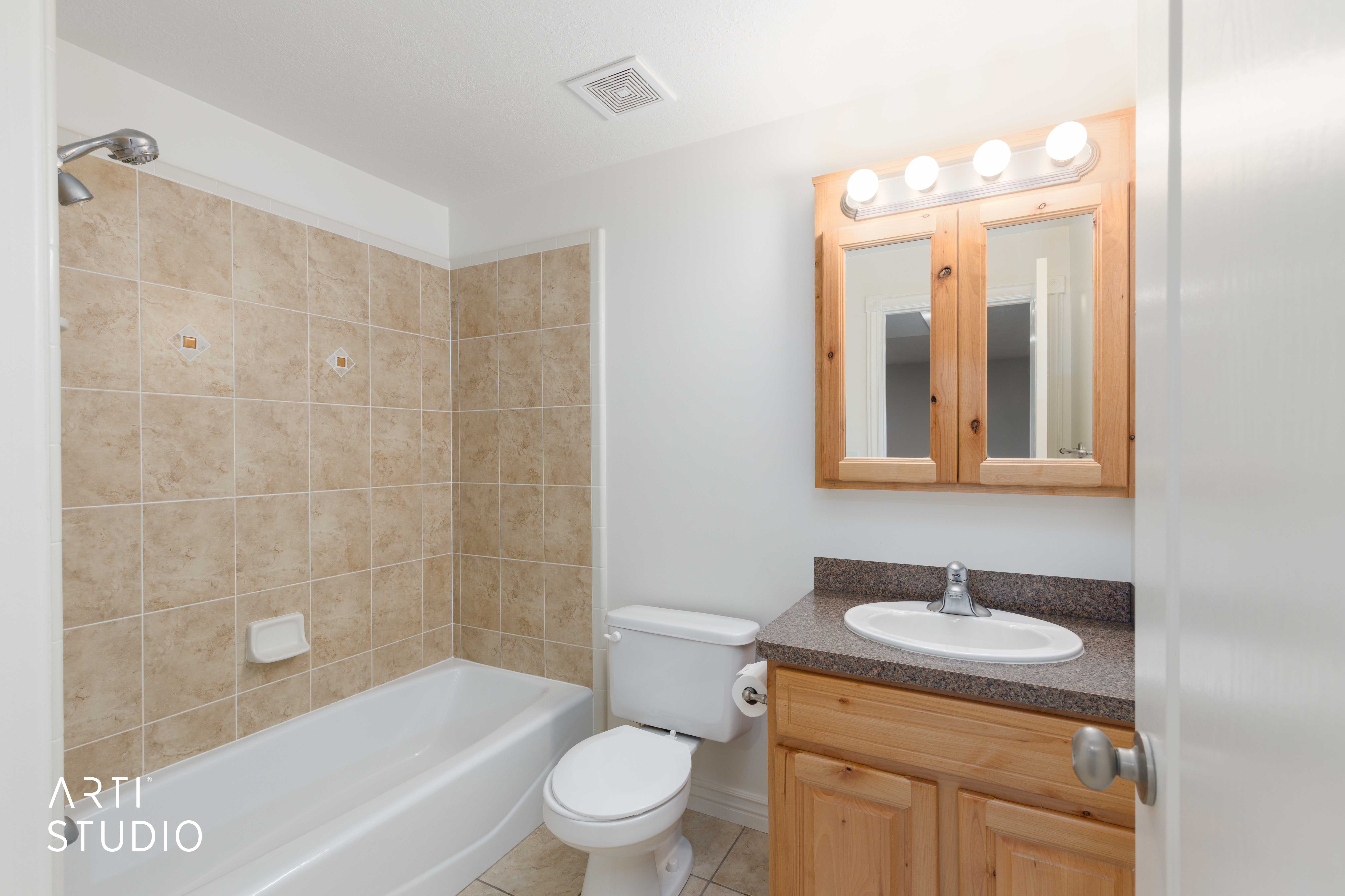 Bathroom featuring a light wood-finish vanity with a built-in sink, an overhead light fixture, and a mirrored medicine cabinet