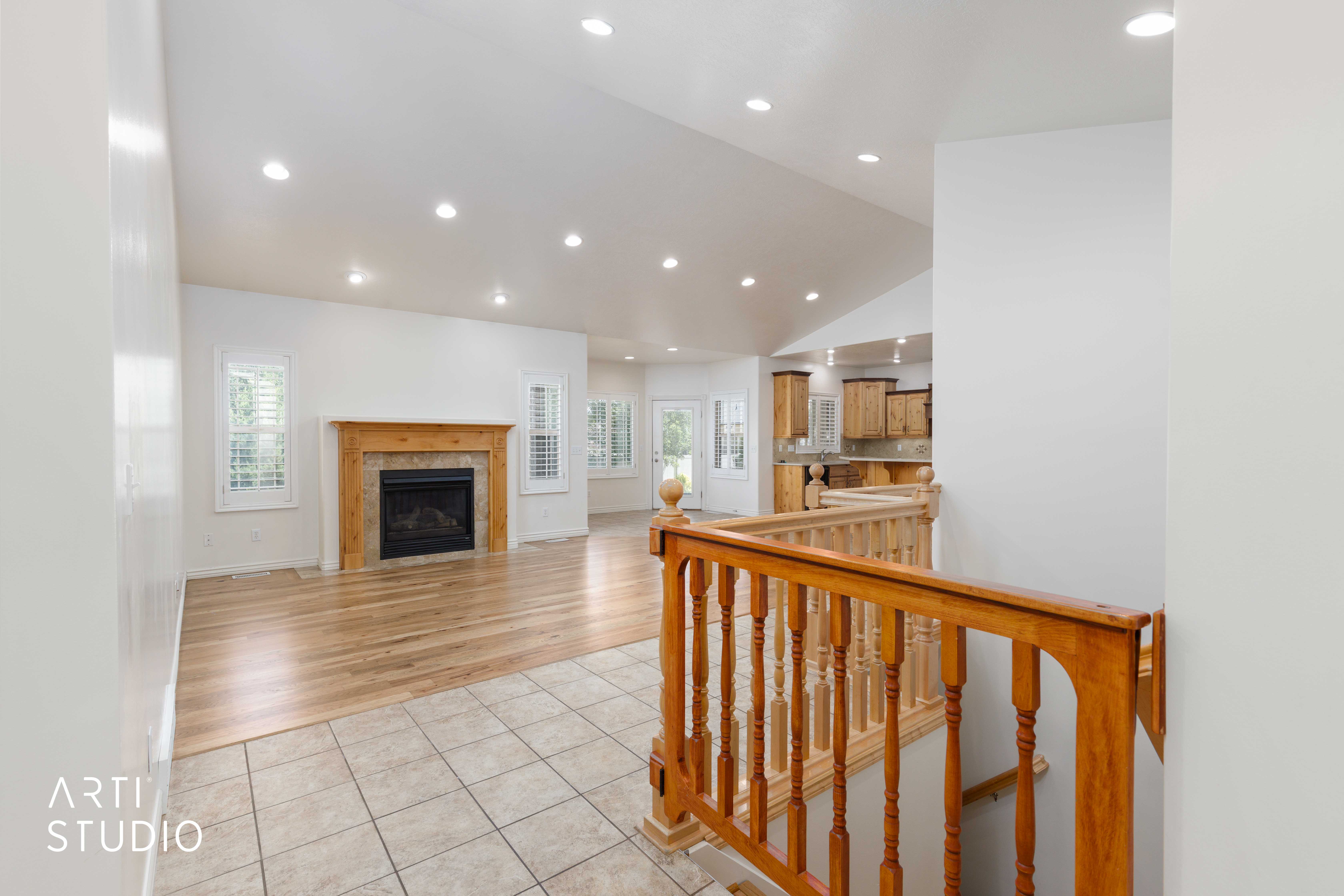 Spacious living area featuring wood-finish flooring, recessed lighting, and a fireplace with a stone surround and wood mantel