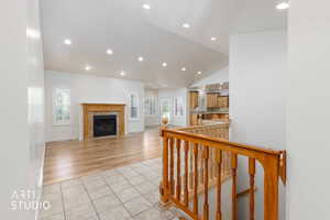 Spacious living area featuring wood-finish flooring, recessed lighting, and a fireplace with a stone surround and wood mantel