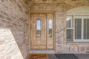 Brick exterior featuring a paneled wood-finish door with decorative glass inserts and an arched transom window