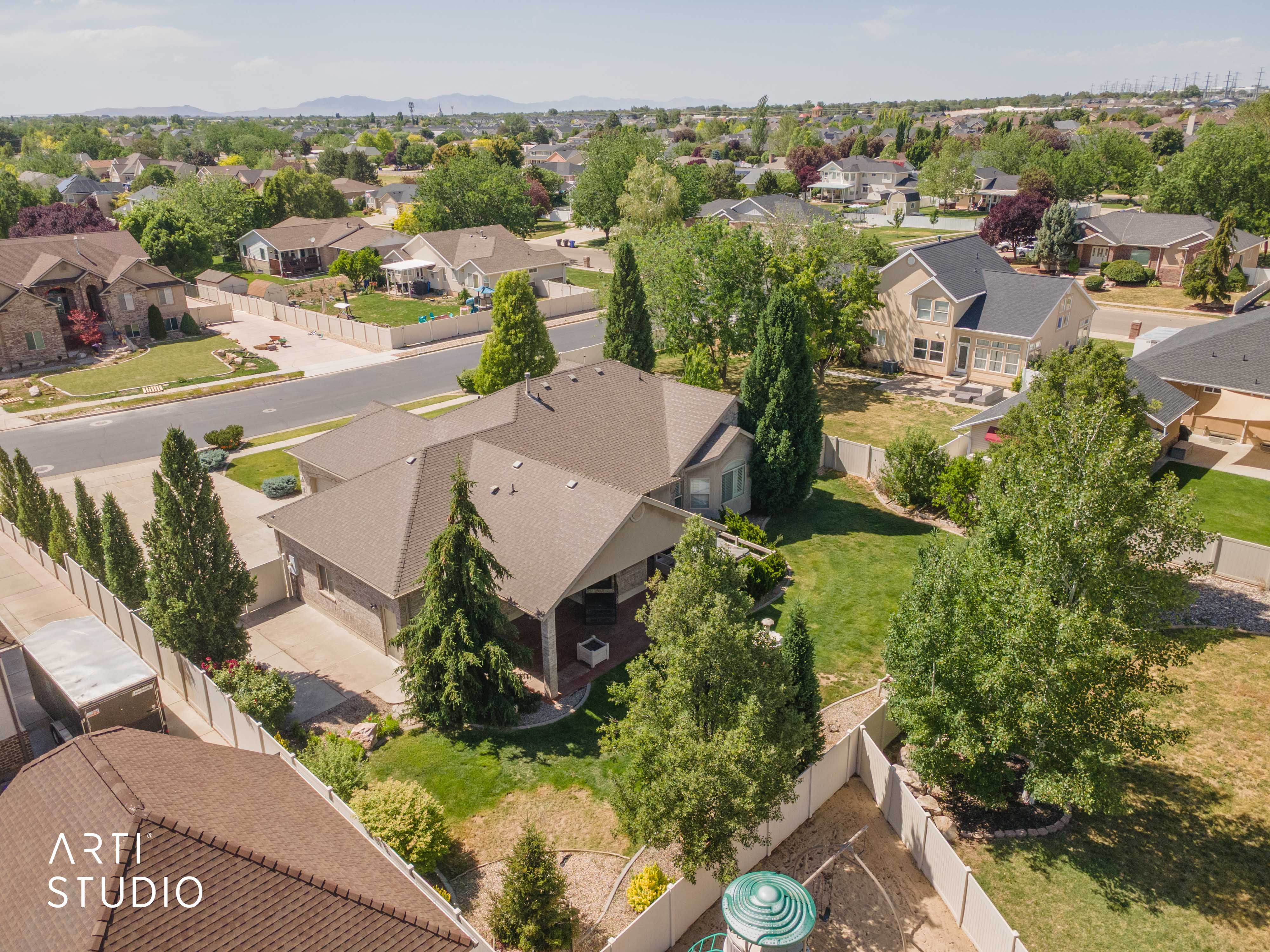 Residential property featuring a spacious backyard, mature trees, and an extended driveway