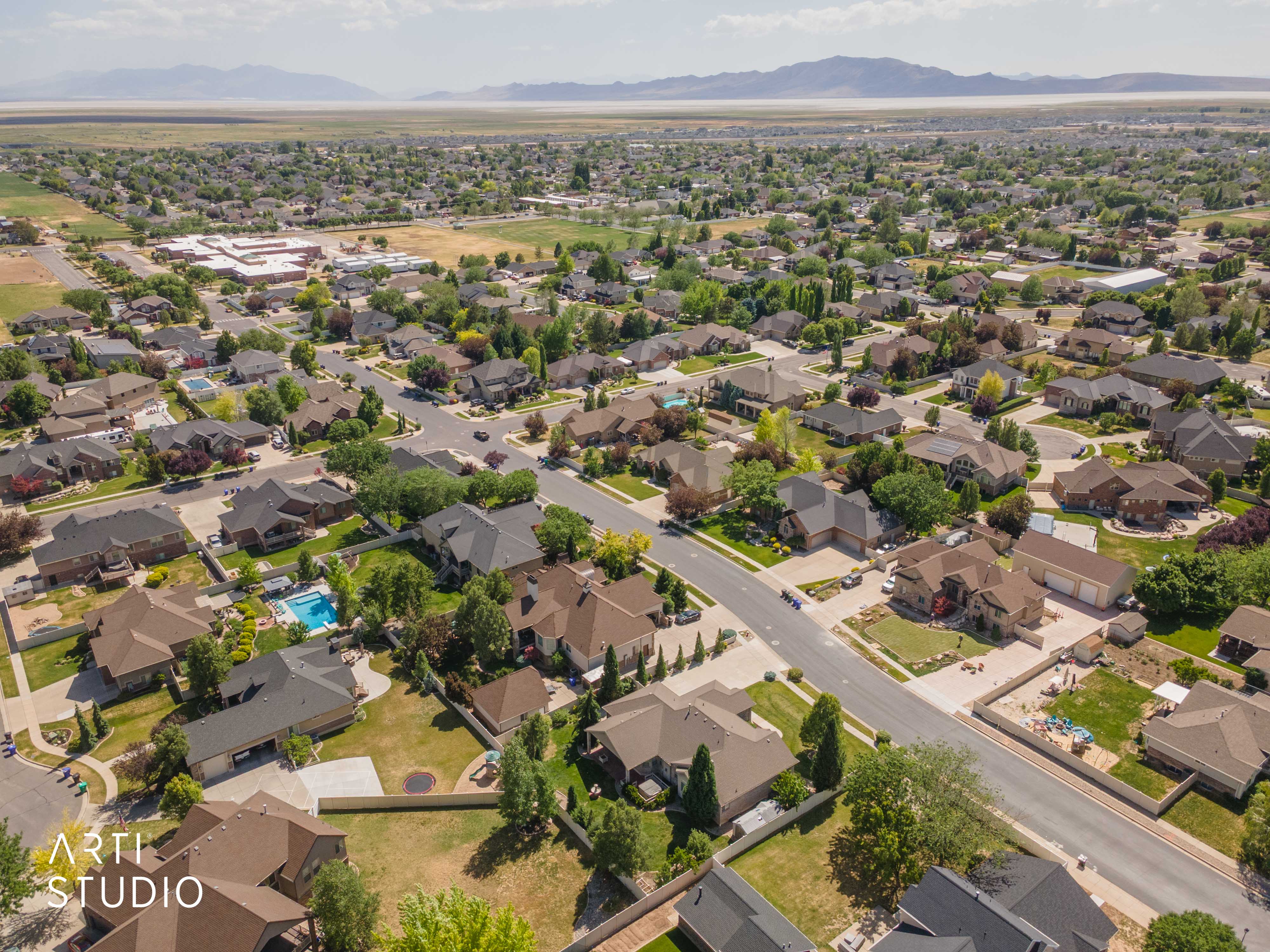Expansive residential neighborhood featuring a variety of single-family homes with pitched roofs, mature landscaping, and an outdoor swimming pool in a private backyard setting