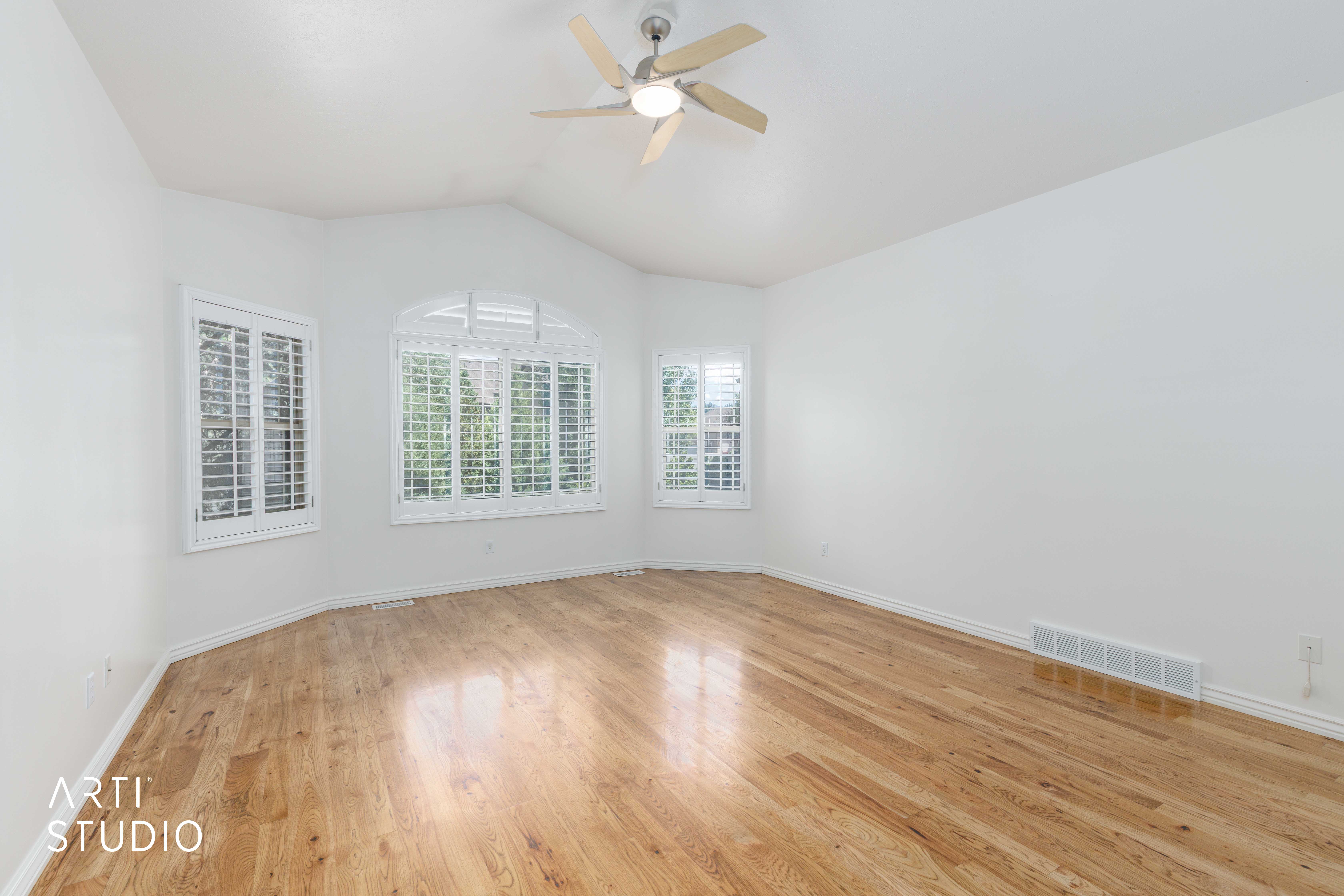 Bright room featuring wood-finish flooring, a vaulted ceiling, and a ceiling fan
