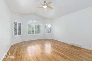 Bright room featuring wood-finish flooring, a vaulted ceiling, and a ceiling fan