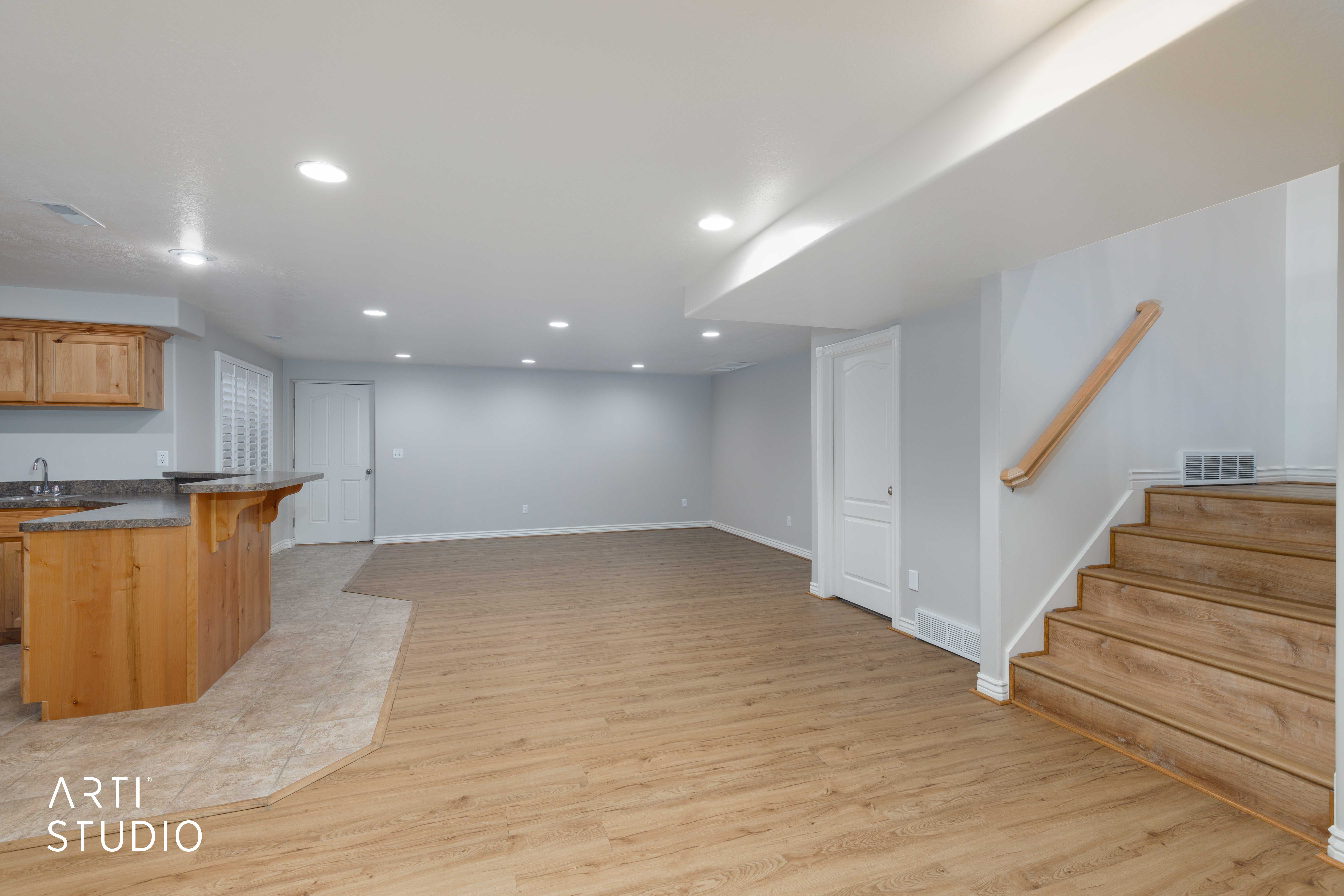 Finished lower level featuring wood-finish flooring, recessed lighting, and a built-in bar with wood cabinetry and a dark stone-finish countertop