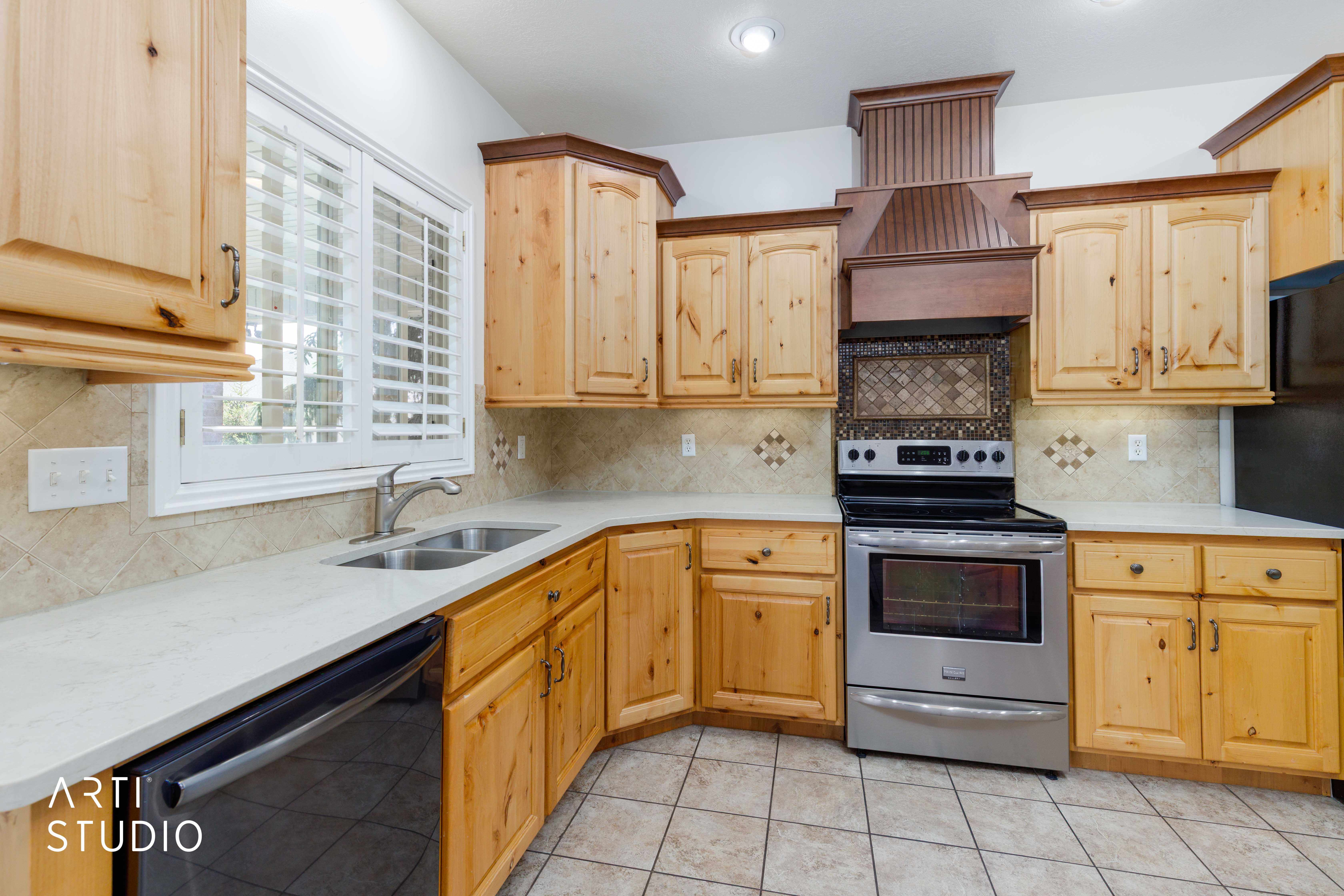 Kitchen featuring knotty pine cabinetry, a stainless steel range with a decorative wood hood, light-toned countertops, a tile backsplash, and ceramic tile flooring