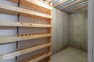 Storage area featuring built-in wooden shelving, a corrugated metal ceiling, and concrete walls